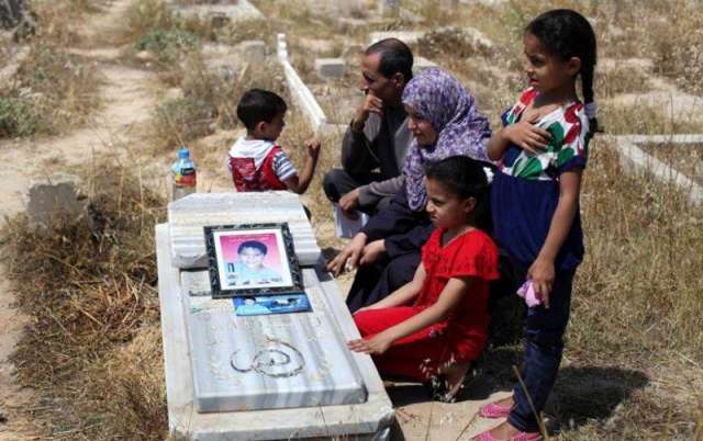 عائلة الشهيد محمد الدرة يجلسون أمام قبره 